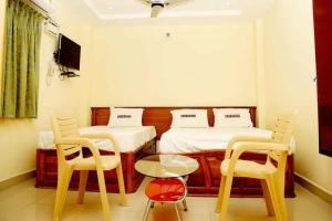 a room with two beds and a table and chairs at Shubhanga Residency in Srikalahasti