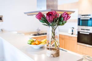 a vase with pink flowers on a counter in a kitchen at Elegant Waterfront Apartment with No Loadshedding in Cape Town