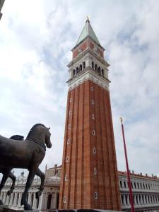 a clock tower with a horse statue in front of it at Apartment Essence of Venice in Venice