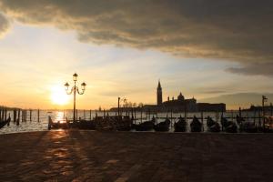 una puesta de sol sobre un muelle con barcos y una torre de reloj en Apartment Essence of Venice, en Venecia