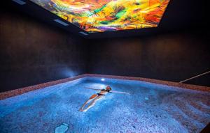 a woman in a swimming pool with a painting on the ceiling at Résidence Prestige Odalys Edenarc in Arc 1800
