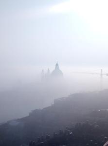 a city in the fog with a bridge in the background at Apartment Essence of Venice in Venice