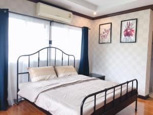 a bedroom with a bed with a metal frame and windows at 24 Hostel Donmuang in Thung Si Kan