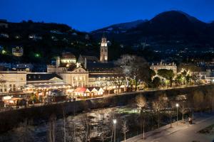 een stad verlicht in de nacht naast een rivier bij Appartment Larcher - Meinhard in Merano