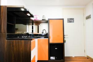 an orange and white kitchen with a sink and a stove at Fully Furnished 2BR Apartment at M-Town Residence By Travelio in Tangerang