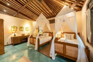 a bedroom with two beds with mosquito nets at Villa Uma Anyar- Joglo Uma in Ubud