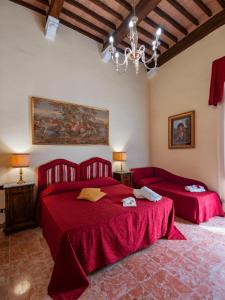 a bedroom with two red beds and a chandelier at B&B Siena In Centro - Diffuso in Siena