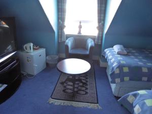 a bedroom with a bed and a table and a chair at Seashells Guest House in Aberdeen