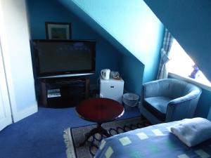a blue room with a television and a chair at Seashells Guest House in Aberdeen