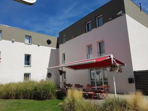 een gebouw met een tafel en een rode paraplu bij ibis Styles Compiegne in Jaux