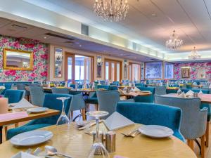 a restaurant with wooden tables and blue chairs at Langstone Cliff Hotel in Dawlish