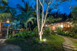 a garden at night with a tree and a pathway at Villa Uma Anyar- Joglo Uma in Ubud