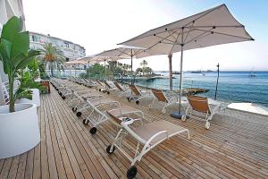 a beach area with chairs, tables and umbrellas at Hotel Náutico Ebeso in Ibiza Town