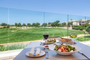 a table with two plates of food and wine glasses at Aphrodite Hills Rentals - Apartments in Kouklia