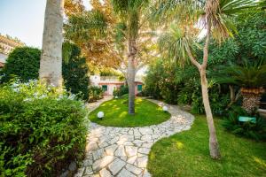 a garden with palm trees and a stone walkway at Hotel Continental Ischia in Ischia