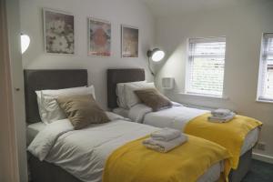 two beds in a room with towels on them at Town Street Apartment in Marple