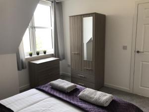 a bedroom with a bed with a dresser and a mirror at Carvetii - Edward House C - 2 Dbl bed 2nd floor flat in Dunfermline