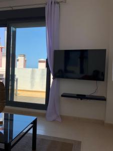 a flat screen tv on a wall next to a window at Family Home Drago Chill Out in Icod de los Vinos