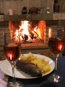 une assiette de poisson et de pommes de terre et deux verres de vin dans l'établissement Guest house Emmy, à Trigrad