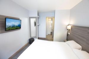 a bedroom with a bed and a tv on the wall at Hipotel Paris Père-Lachaise République in Paris