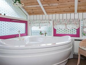a white tub in a bathroom with pink walls and windows at 8 person holiday home in Glesborg in Fjellerup
