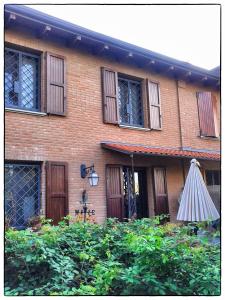 uma casa de tijolos com um guarda-chuva em frente em La Corte del Macero em Castelfranco Emilia