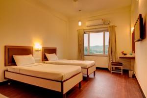 a hotel room with two beds and a window at Ramoji Greens Inn in Pedda Ambarpet