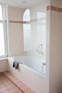 een witte badkamer met een bad en een raam bij Het Rechthuis in Uithoorn