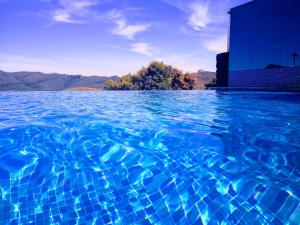 a pool of blue water with a building in the background at Hotel Recanto do Ouro in Ouro Preto