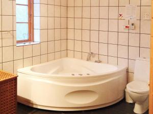 El baño incluye bañera blanca y aseo. en Three-Bedroom Holiday home in Hadsund 28, en Odde