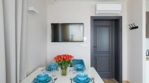 a white table with blue dishes and a vase of flowers at Apartamenty.in Chałupy in Chałupy