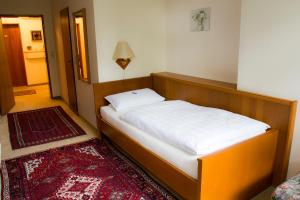 a small bed in a room with a red rug at Hotel Haus am See in Bad Salzuflen