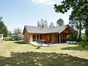 una pequeña cabaña de madera con una mesa de picnic en un patio en Three-Bedroom Holiday home in Hadsund 28, en Odde