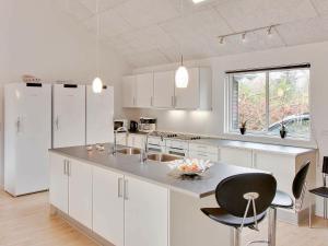 a kitchen with white cabinets and a sink and a counter at 24 person holiday home in Bl vand in Blåvand
