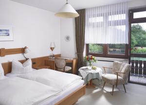 Schlafzimmer mit einem Bett, einem Tisch und Stühlen in der Unterkunft Hotel Haus am See in Bad Salzuflen