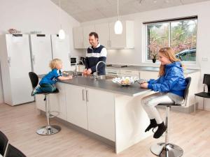 a man and a woman and a child sitting at a kitchen counter at 24 person holiday home in Bl vand in Blåvand