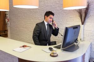 a man talking on a phone in front of a desk with a computer at Casale Santa Maria Country House in Mosciano SantʼAngelo