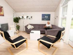 a woman sitting on a couch in a living room at 9 person holiday home in Brovst in Brovst