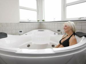 a woman sitting in a bath tub in a bathroom at 9 person holiday home in Brovst in Brovst