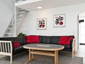 エーベルトフトにある8 person holiday home in Ebeltoftのリビングルーム(黒いソファ、テーブル付)