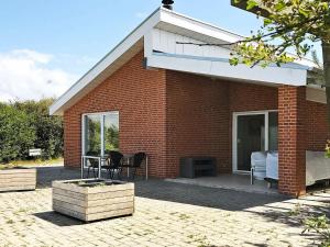 Sønder YdbyにあるTwo-Bedroom Holiday home in Thyholm 6のレンガ造りの家で、パティオ(テーブル、椅子付)が備わります。