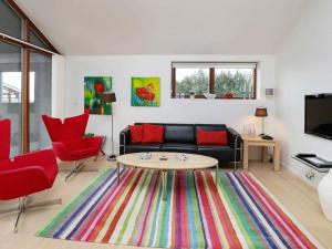 ボーゲンセにある4 person holiday home in Bogenseのリビングルーム(黒いソファ、赤い椅子付)