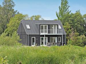 a black house on top of a grassy field at Luxury Spa Retreat by Sea in Humble