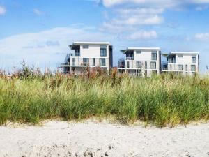 two houses on the beach with tall grass at 6 person holiday home in Wendtorf in Wendtorf