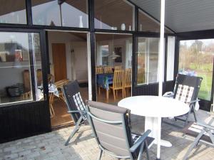 eine Terrasse mit einem weißen Tisch und Stühlen sowie einem Tisch und Fenstern in der Unterkunft 4 person holiday home in Broager in Broager