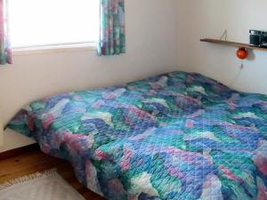 a bed in a bedroom with a colorful comforter at 6 person holiday home in V ggerl se in Marielyst