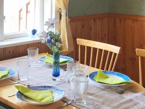 una mesa con platos y vasos y un jarrón de flores en One-Bedroom Holiday home in Sjötorp, en Otterbäcken