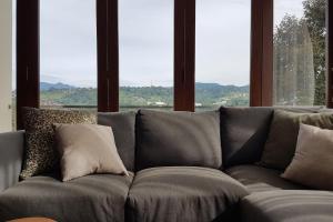 a gray couch with pillows in a room with windows at Bukit Dago Palace 22 in Bandung