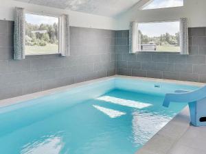 a large blue swimming pool in a room with two windows at 24 person holiday home in Stege in Stege