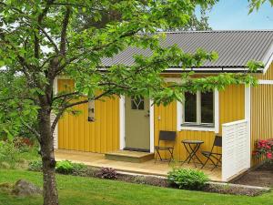 una pequeña casa amarilla con mesa y sillas en One-Bedroom Holiday home in Sjötorp, en Otterbäcken